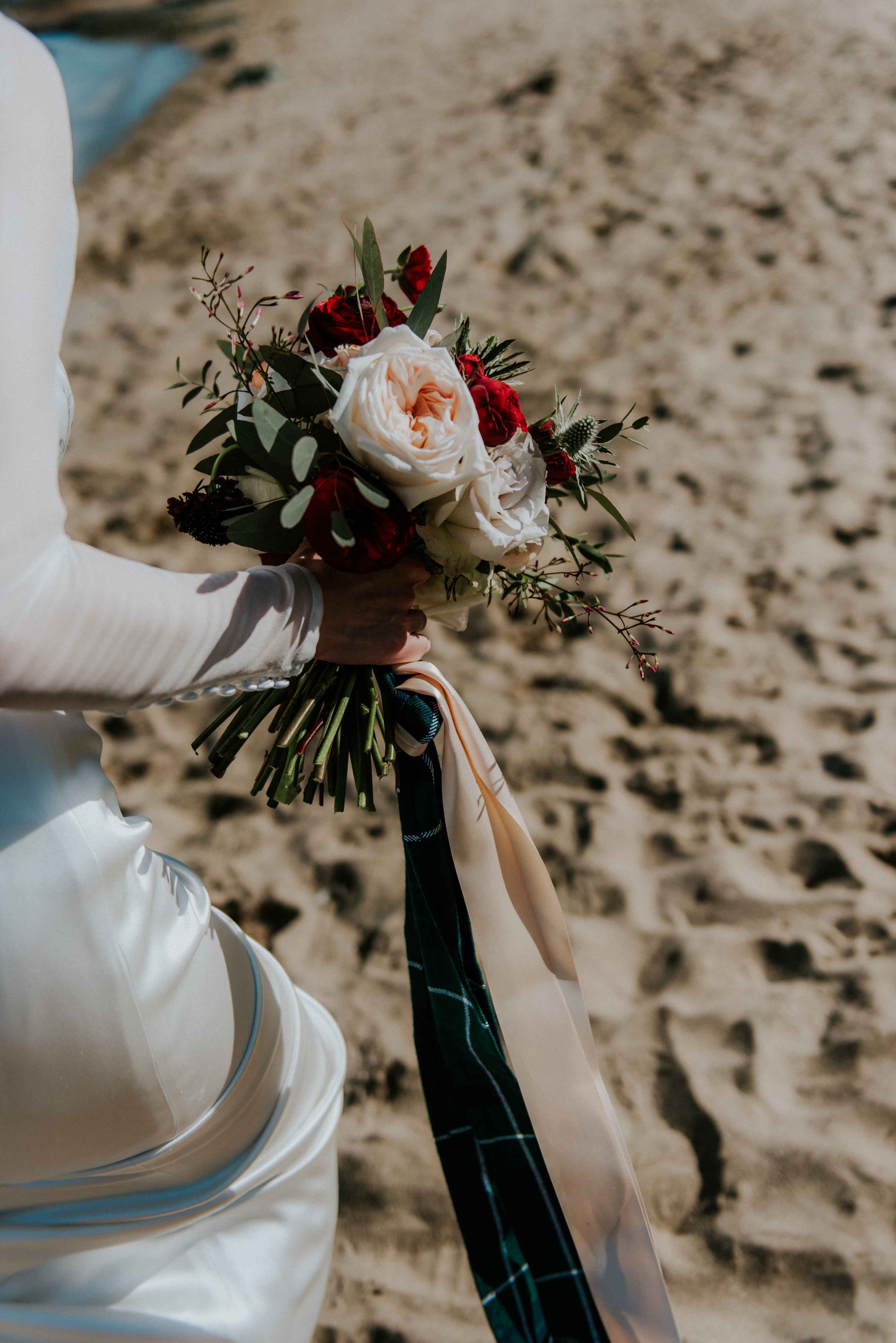 Woman holding a bouquet of flowers on the beach.
